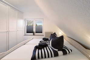 Un dormitorio con cama, ventana con persianas y un radiador.