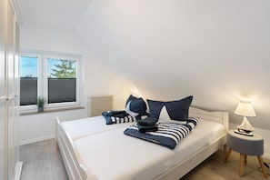 Un dormitorio con cama, mesita de noche, lámpara, ventana y radiador.