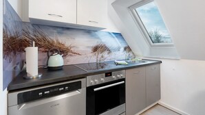 A modern kitchen with a built-in dishwasher, oven, and a large window.