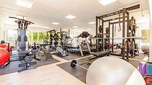 Une salle de sport équipée de divers appareils d’exercice, notamment des tapis de course, des appareils de musculation et des poids libres.
