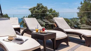 Un espace de détente aménagé sur le toit, avec des fauteuils confortables, une table, une boisson et un livre.