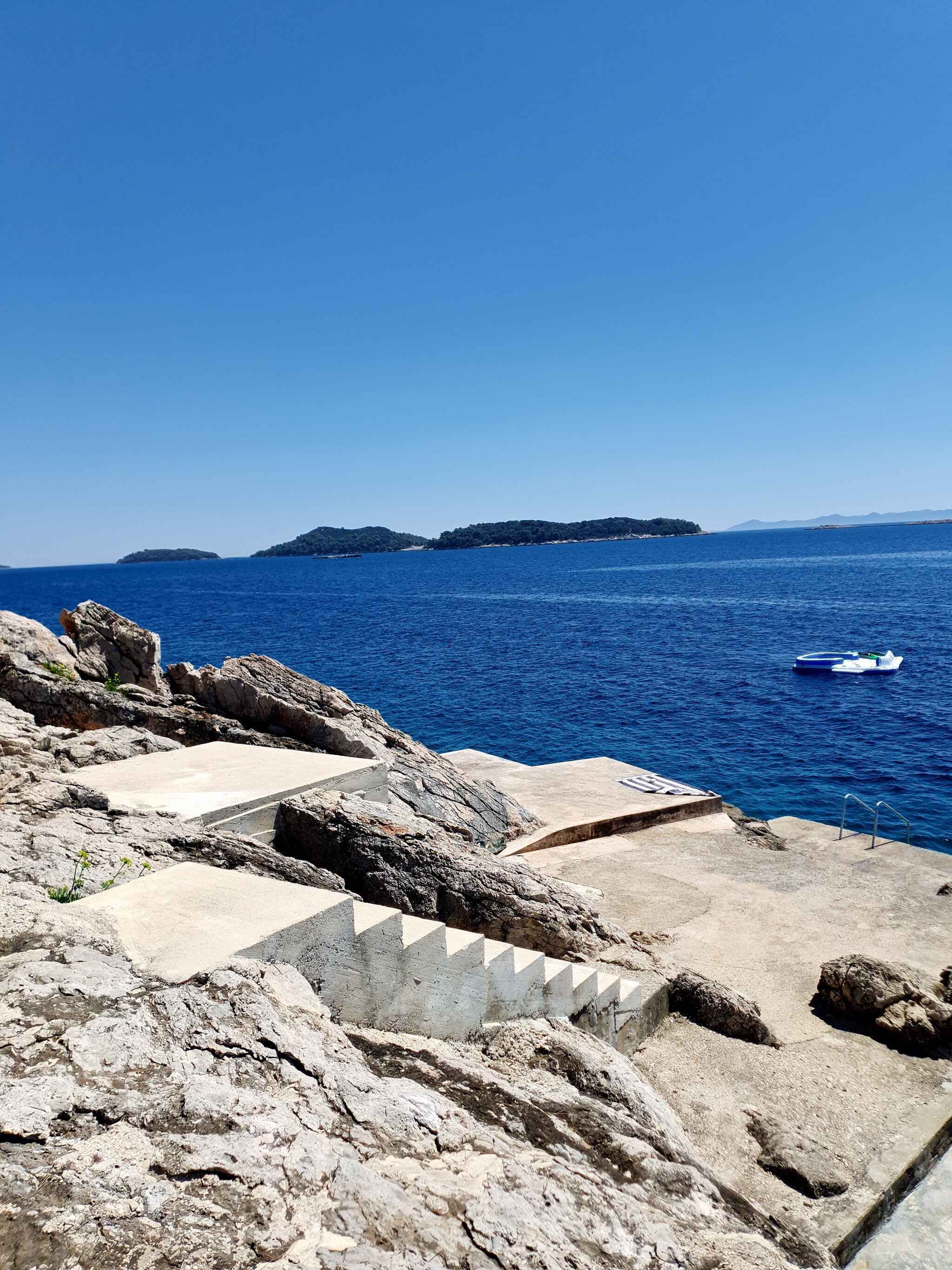 A coastal view with rocky terrain and a clear blue sea.