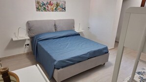 Un dormitorio con cama, mesitas de noche, un cuadro colgado en la pared y suelo de madera.