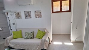 Una sala de estar moderna con un sofá, una mesa de centro de vidrio y obras de arte en la pared.