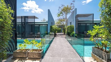 A modern pool area with glass railings, a clear pathway, and potted plants.