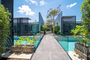 Un'area piscina moderna con ringhiere in vetro, un percorso accessibile e piante in vaso.