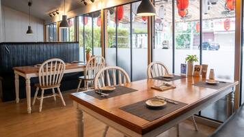A restaurant interior with a wooden dining table, chairs, and a booth seating area.