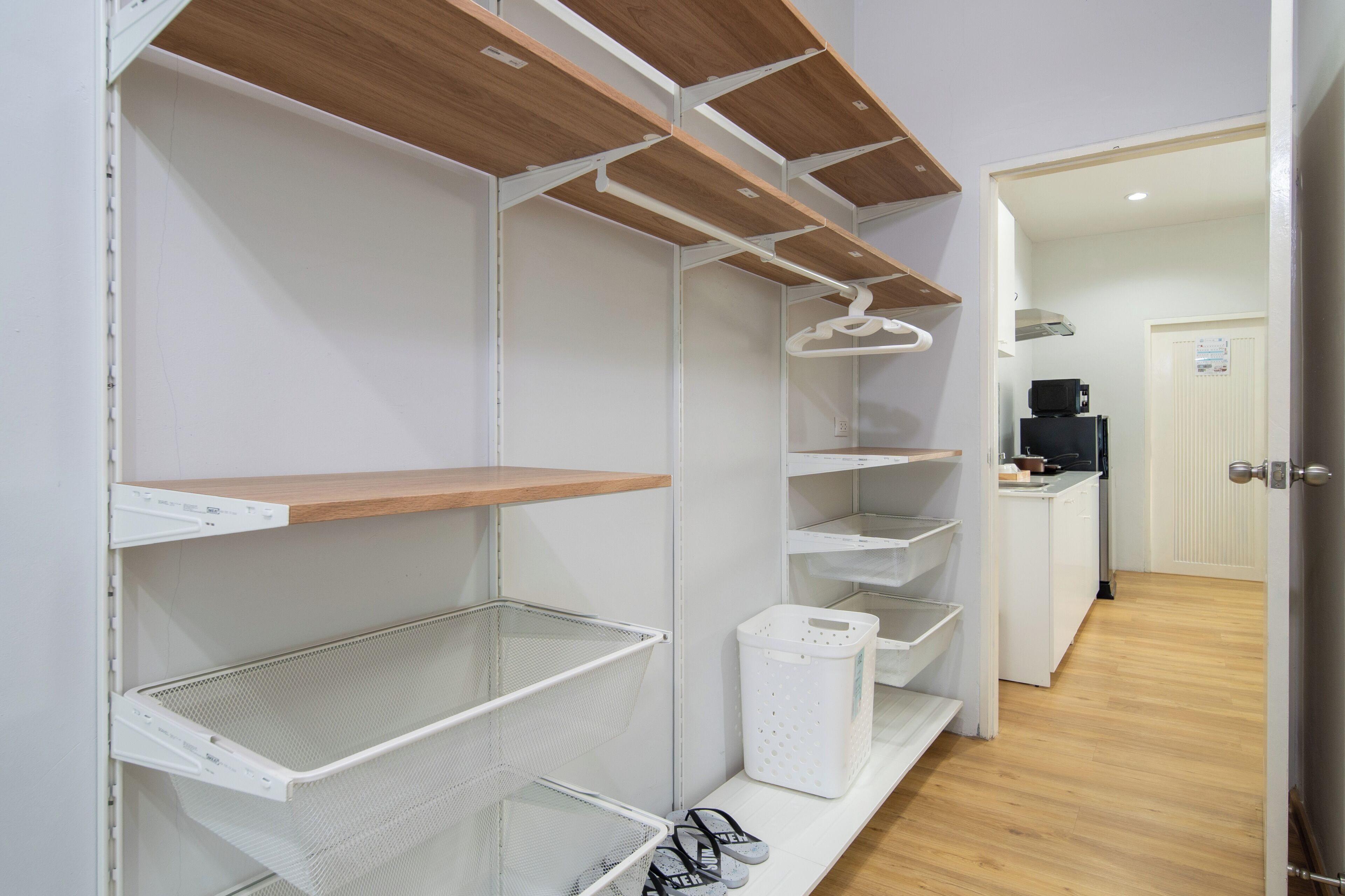 Una cocina limpia y moderna con armarios blancos, repisas de madera y un microondas.