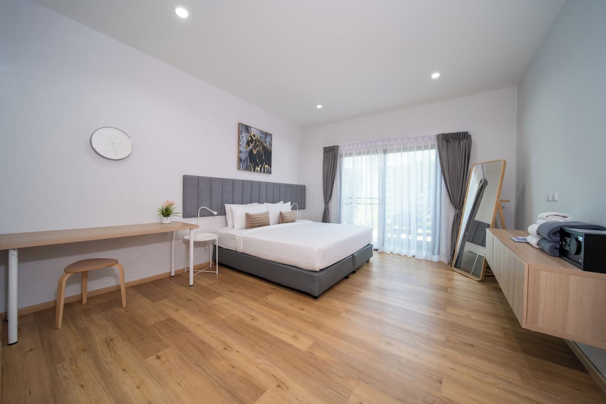 Un dormitorio moderno con cama, escritorio, silla y un amplio ventanal con cortinas.