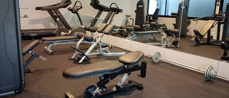A gym with various exercise equipment, including treadmills, a bench press, and a squat rack.