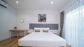 Un dormitorio moderno con una cama grande, un escritorio y una silla, un reloj en la pared y una ventana con cortinas.