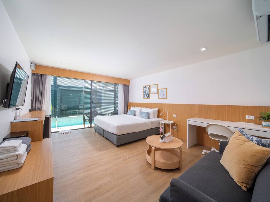 A modern hotel room with a bed, desk, and seating area.
