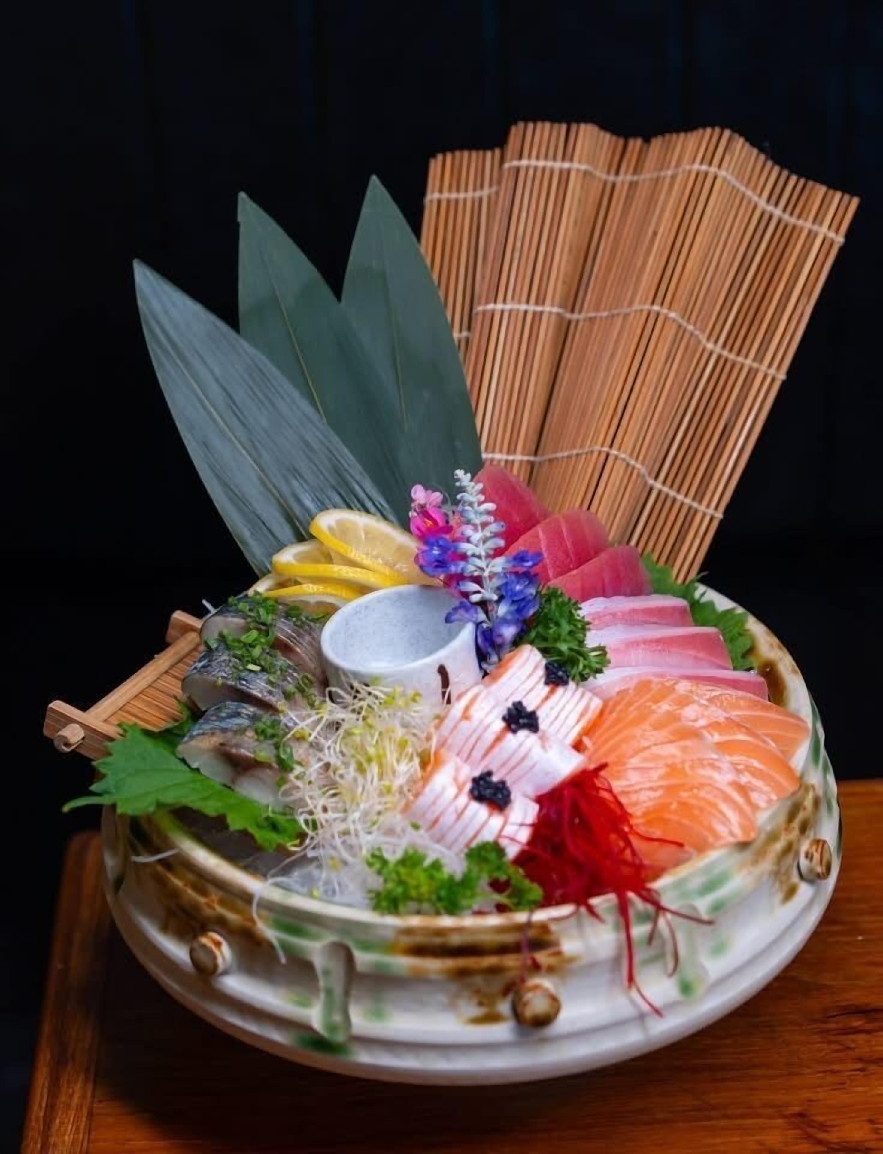 A traditional Japanese sashimi platter with various fish slices, garnishes, and a small bowl of sauce.