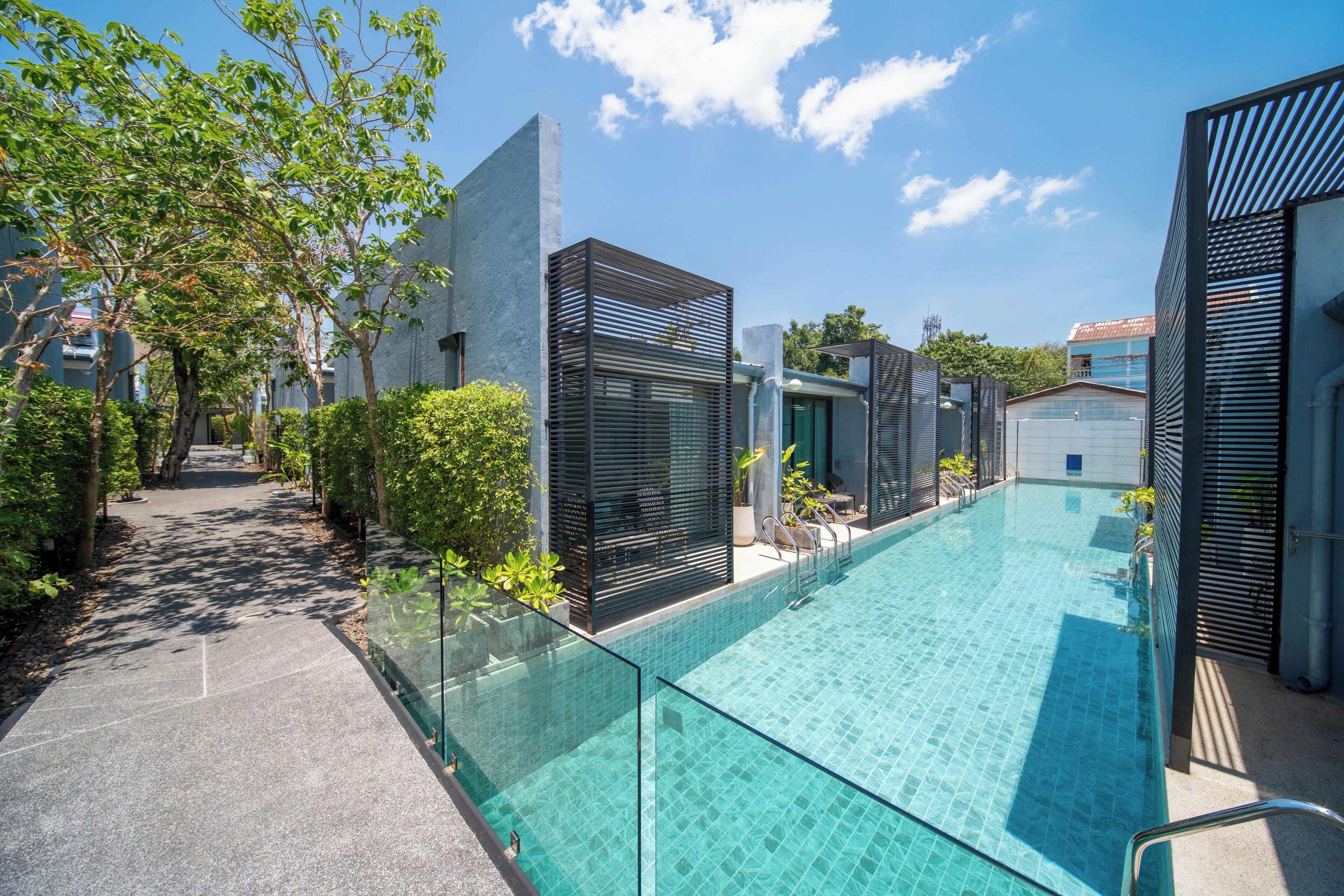 Un área de piscina moderna con agua cristalina, rodeada de barandillas de vidrio y arquitectura contemporánea.