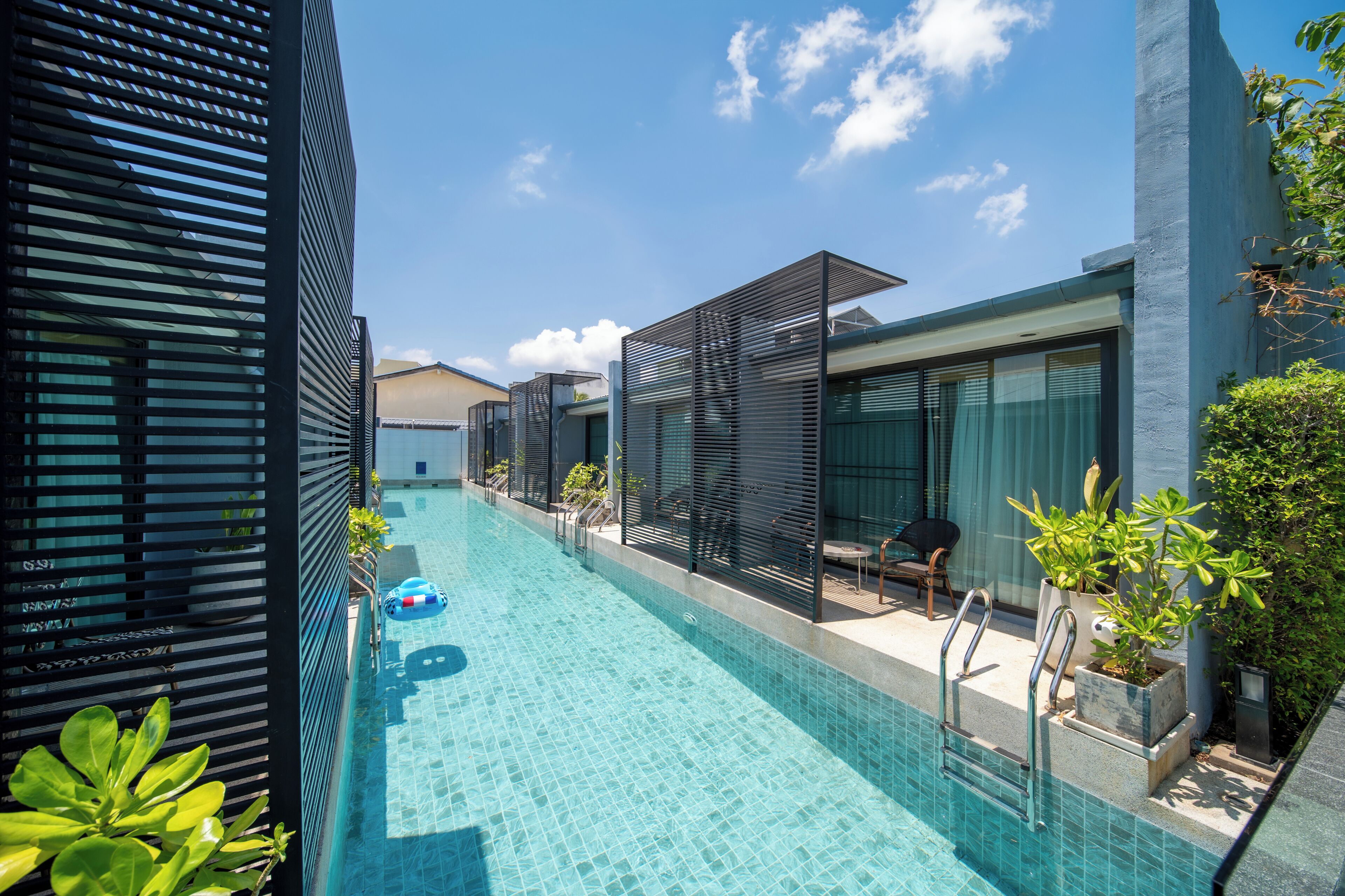 A modern hotel with a swimming pool, outdoor seating, and a view of the sky.