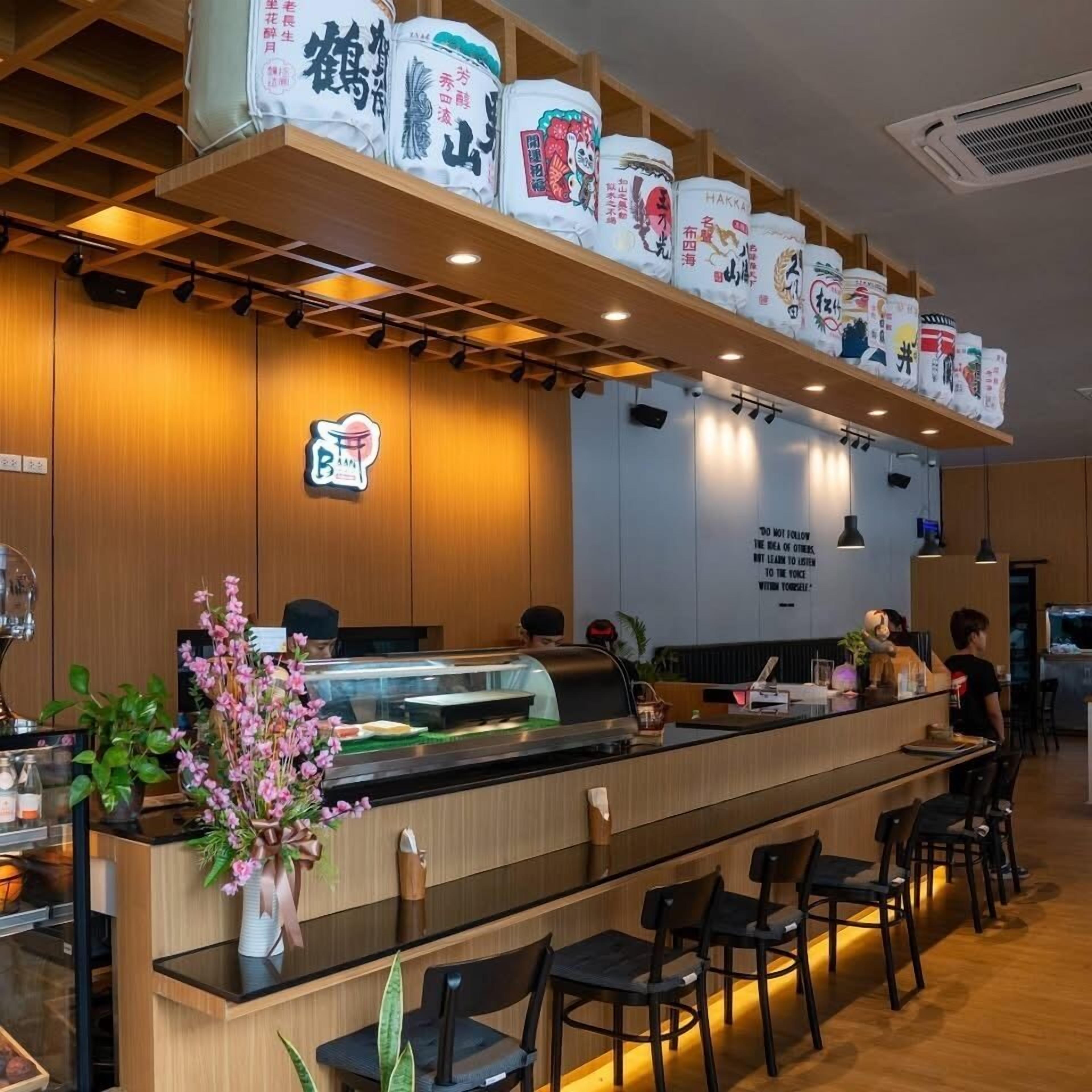 A restaurant interior with a long counter, wooden paneling, and a display of packaged goods above.