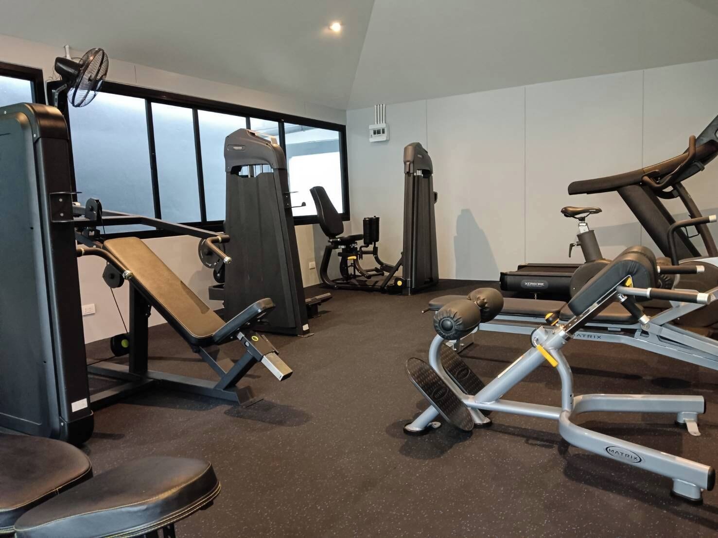 A gym with various exercise equipment, including a bench press, leg press, and a treadmill.
