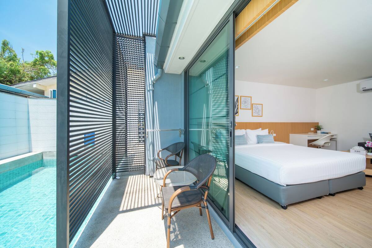 Una habitación de hotel moderna con balcón, una cama, un escritorio y una silla.
