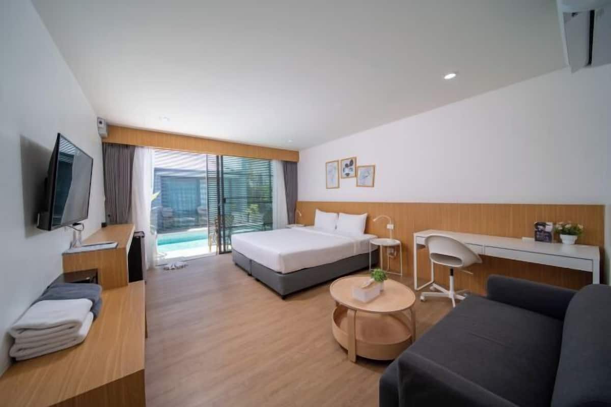 Habitación de hotel moderna con cama, escritorio, televisor y vistas al exterior.