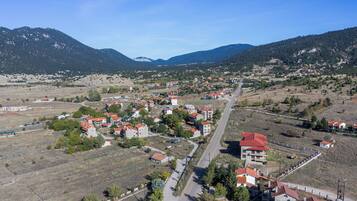A town with a main road, buildings with red roofs, and mountains in the background.