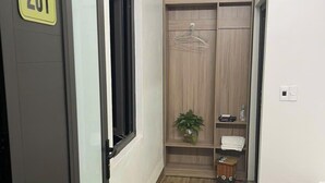 Habitación de hotel con armario, planta en maceta y cama.
