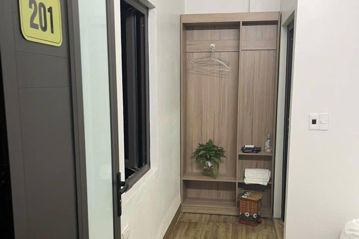 Ein Hotelzimmer mit Kleiderschrank, Topfpflanze und einem Bett.