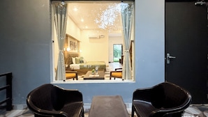 A room with a large window, a bed, a table, and two chairs. - The Kiaan Corbett Resort (Ramnagar)