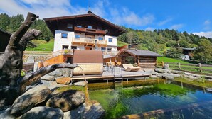 Ein traditionelles Chalet mit Holzterrasse, Teich und Bergblick.