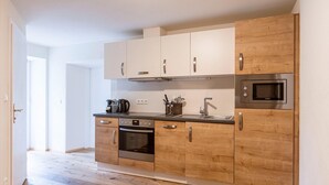 Eine moderne Küche mit Holzausstattung, einem Backofen, einer Mikrowelle und einem Wasserkocher.