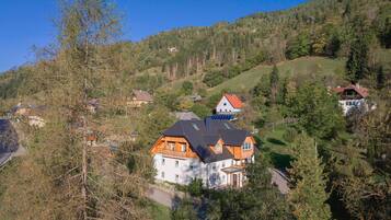 Eine Wohngegend an einem Hang mit mehreren Häusern, darunter ein auffälliges Haus mit geneigtem Dach und Holzfassade.