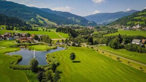 Ländliche Landschaft mit einem kleinen Dorf, grünen Feldern, einem Teich und einer Kirche.
