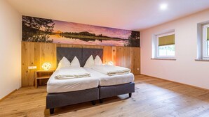 Ein Schlafzimmer mit einem Bett, einem Nachttisch, einer Wandlampe und einem Fenster.