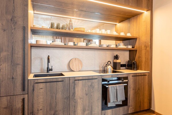 A modern kitchen with wooden cabinetry, a stainless steel sink, and a built-in oven.
