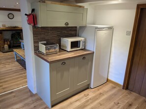 Compact kitchen with microwave oven, toaster, and refrigerator.