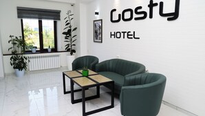 Een moderne hotel lobby met een groene bank, een houten salontafel en een potplant.