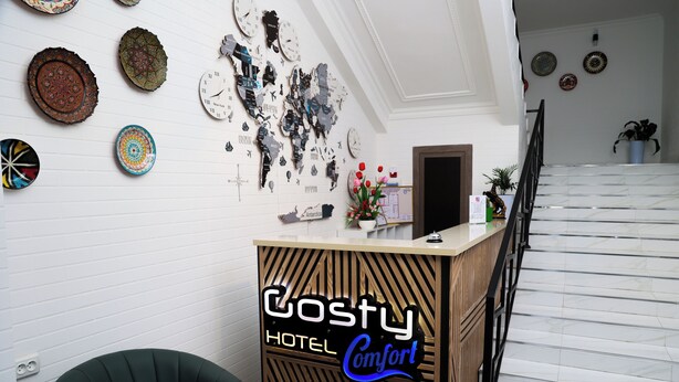 Een houten receptiebalie van een hotel, met een bord waarop 'Costy Hotel Comfort' staat.