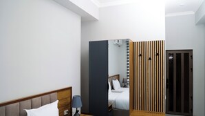 Een moderne hotelkamer met een groot bed, nachtkastjes, een spiegel en een kledingkast.