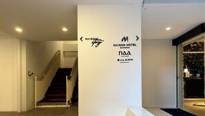 Rebedor d'hotel amb una escala, una taquilla d'informació i un cartell de Maison Hotel Bangkok.