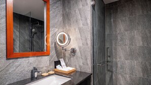 Un bany modern amb un lavabo de marbre, un mirall amb marc de fusta, un vàter de mà i una dutxa amb portes de vidre.