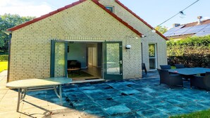 A small brick house with a sloped roof, a sliding glass door entrance, a patio with a table and chairs, and a solar panel on the roof. - Holiday home in Ewijk in a beautiful area (Ewijk)