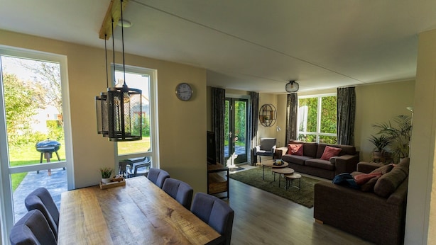Un vaste espace de vie comprenant une table à manger en bois, des canapés et une vue sur l’extérieur.