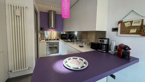 A modern kitchen with a purple countertop, a pink hanging light, a coffee maker, and a corkboard with notes. - Charming Tuscan Home with Pool near Lucca (Lucca)