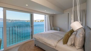 A bedroom with a large bed, a view of the sea, and a balcony with a railing. - Villa Simpleza - Six Bedroom Villa with Private Pool and Jacuzzi (Klek)