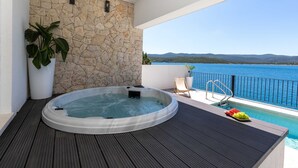 A hot tub on a balcony with a stone wall, a pool, and a view of the sea. - Villa Simpleza - Six Bedroom Villa with Private Pool and Jacuzzi (Klek)