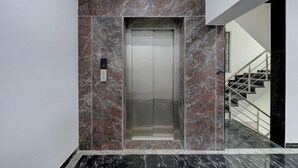 Ein Aufzug in einem modernen Gebäude mit Marmorwänden und einer Metalltreppe.