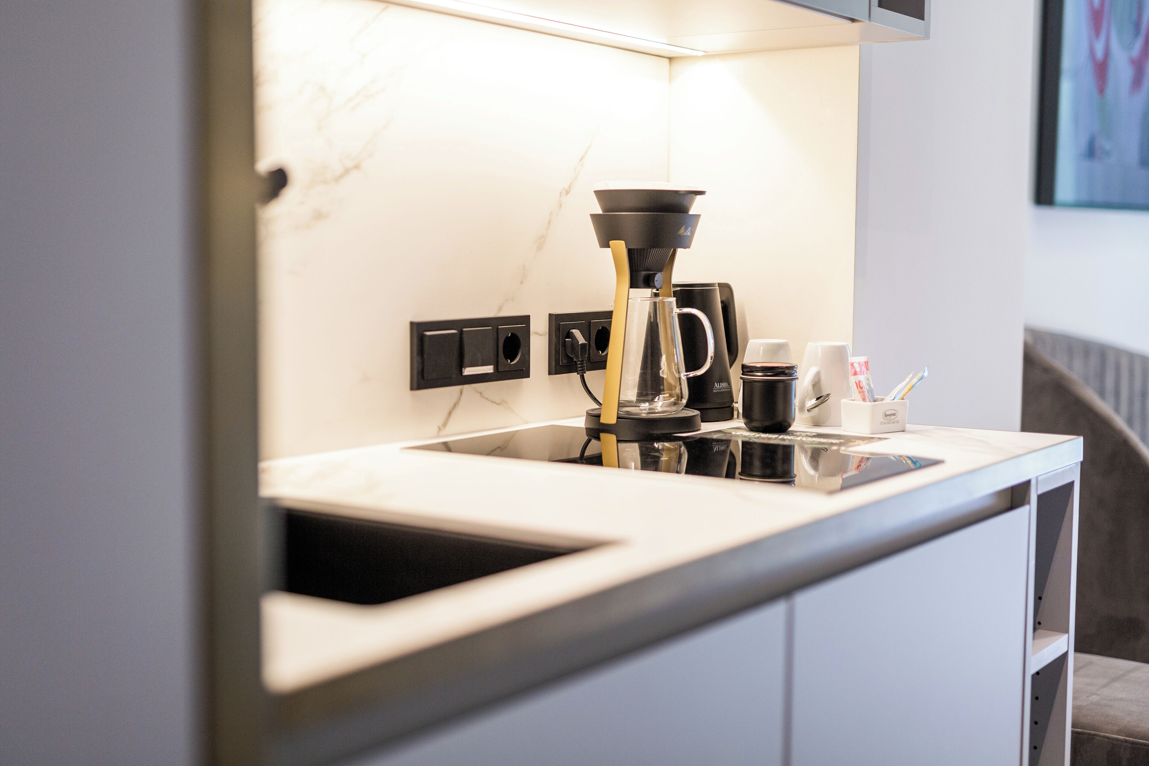 Una cocina moderna con cafetera, lavaplatos y encimera.