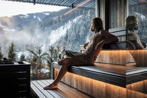 A person sitting on a wooden bench with a view of a snowy mountain landscape.