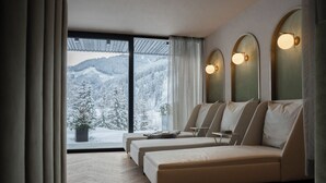 Une chambre moderne avec un canapé-lit, une petite table et une vue sur des arbres couverts de neige.
