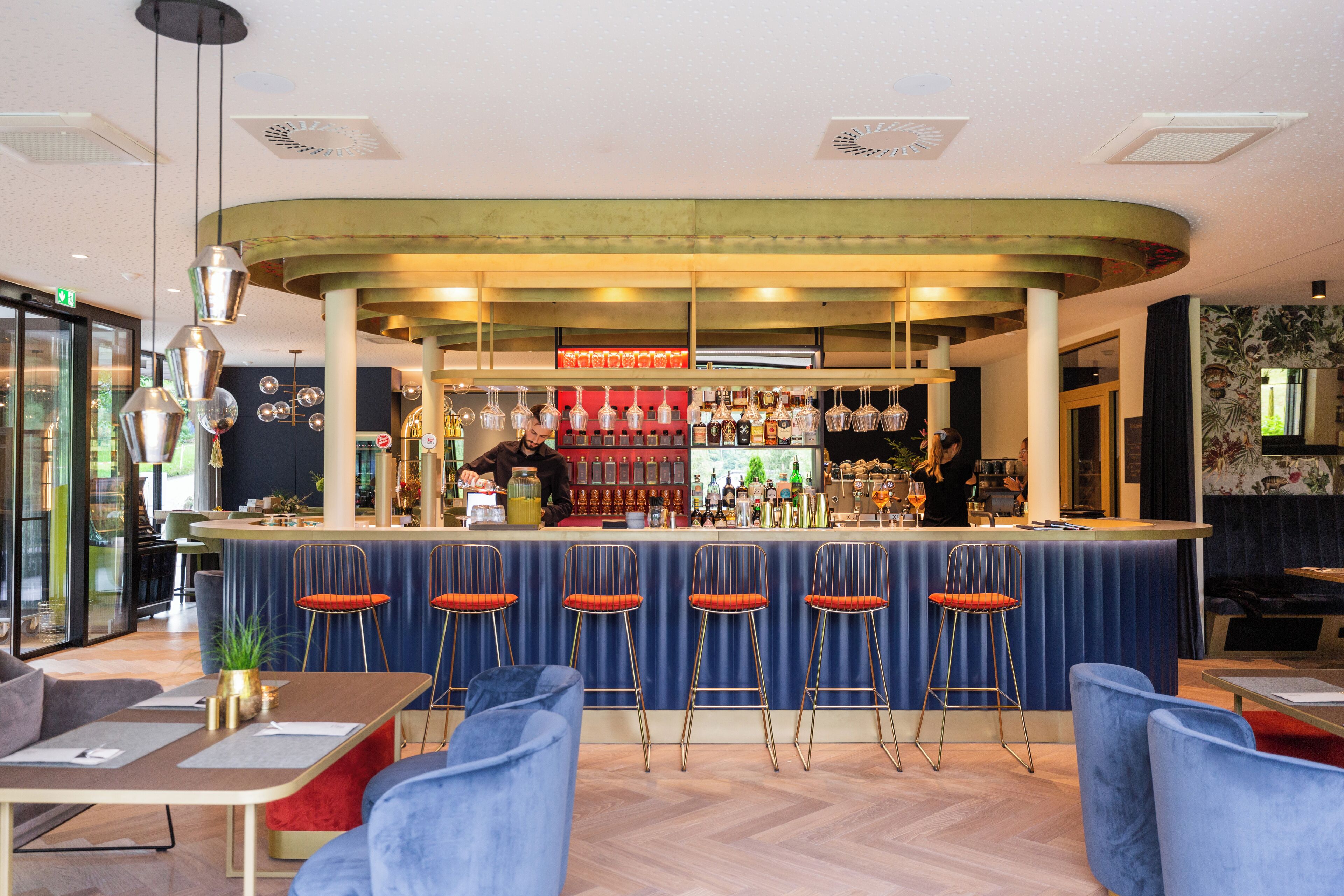 A bar area with a curved counter, bar stools, and a bartender.