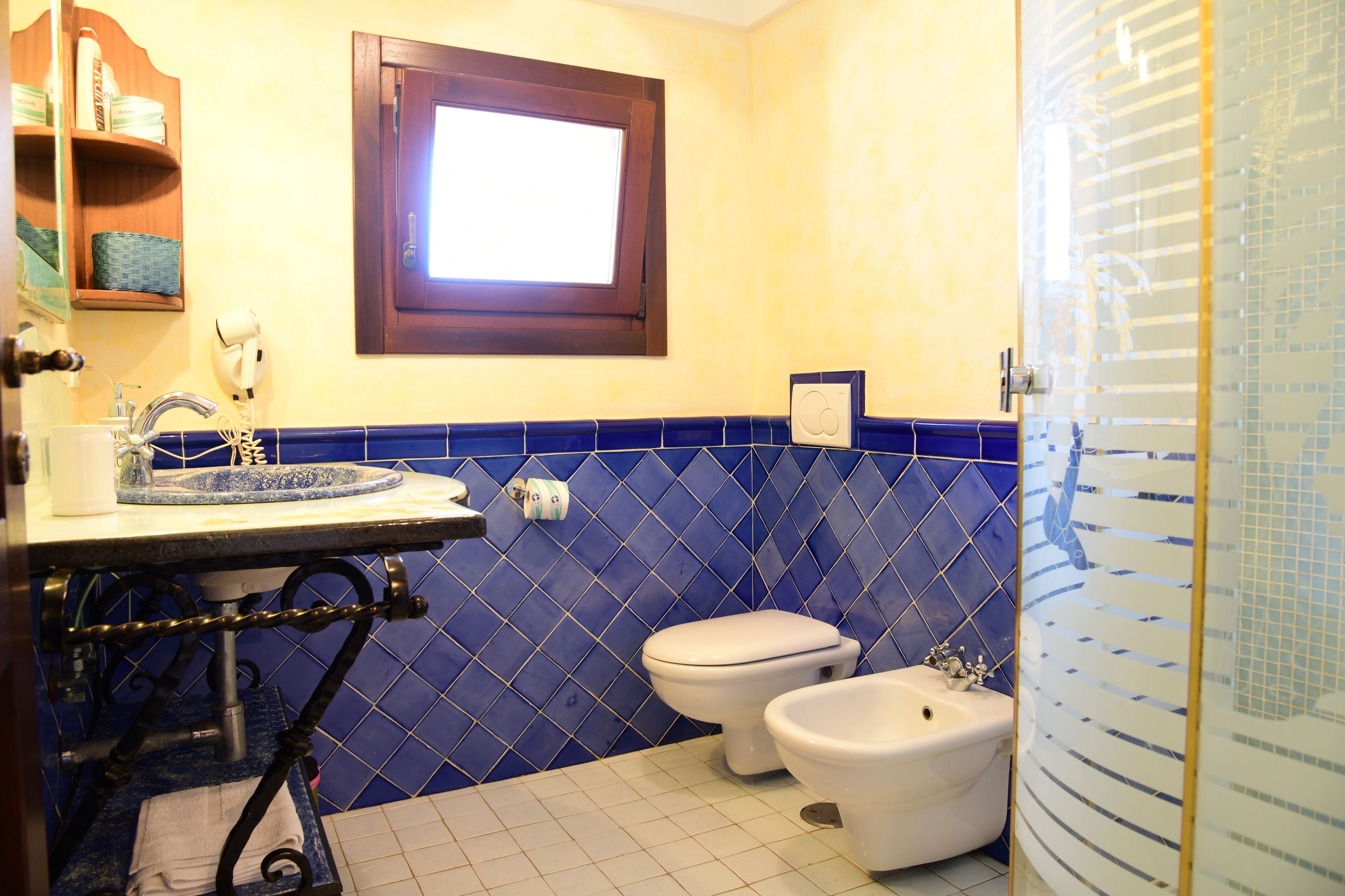 A bathroom with a sink, two toilets, and a window.